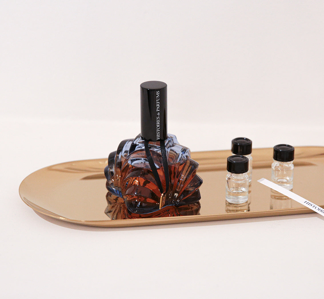 Perfume bottle and vials on a gold tray with a white background